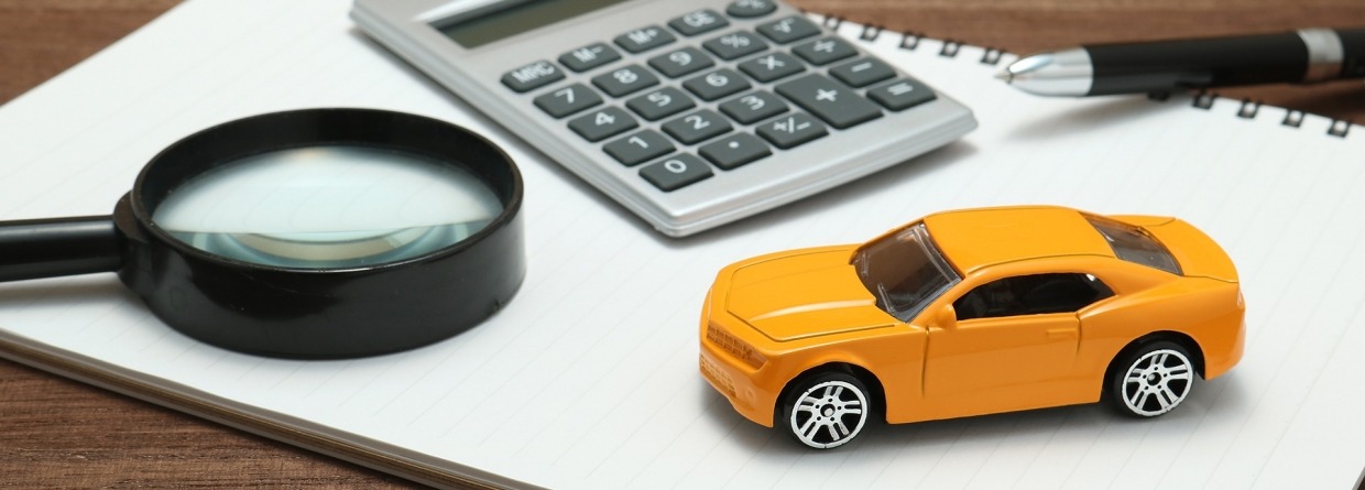 Notitieblok waarop een speelgoedauto, vergrootglas, rekenmachine en pen ligt