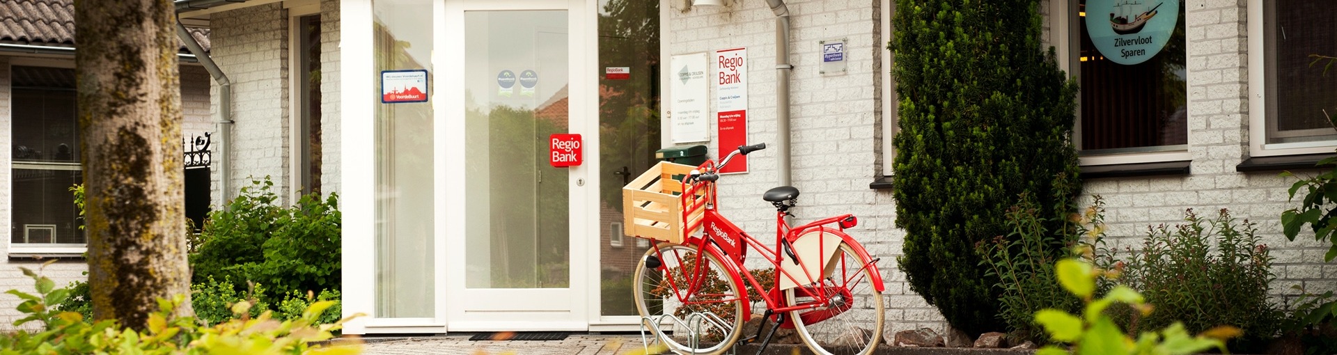 De ingang van het kantoor van Coppis & Cruijsen met voor de deur een rode fiets van RegioBank geparkeerd